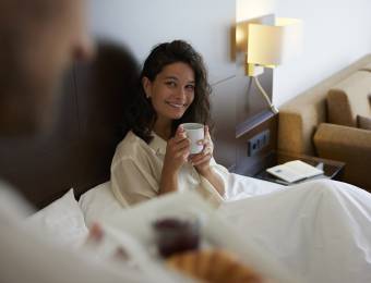 Frau mit Tasse im Bett Sauerland Stern Hotel Willingen