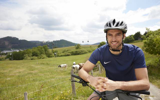 Mountainbiker vor einer Wiese mit Kühen im Sauerland