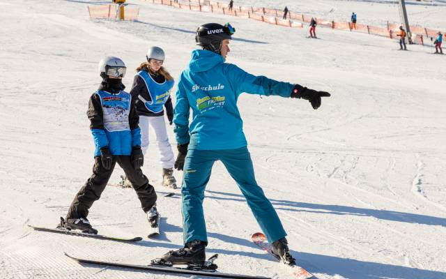 Skifahrer mit Skilehrer auf der Piste
