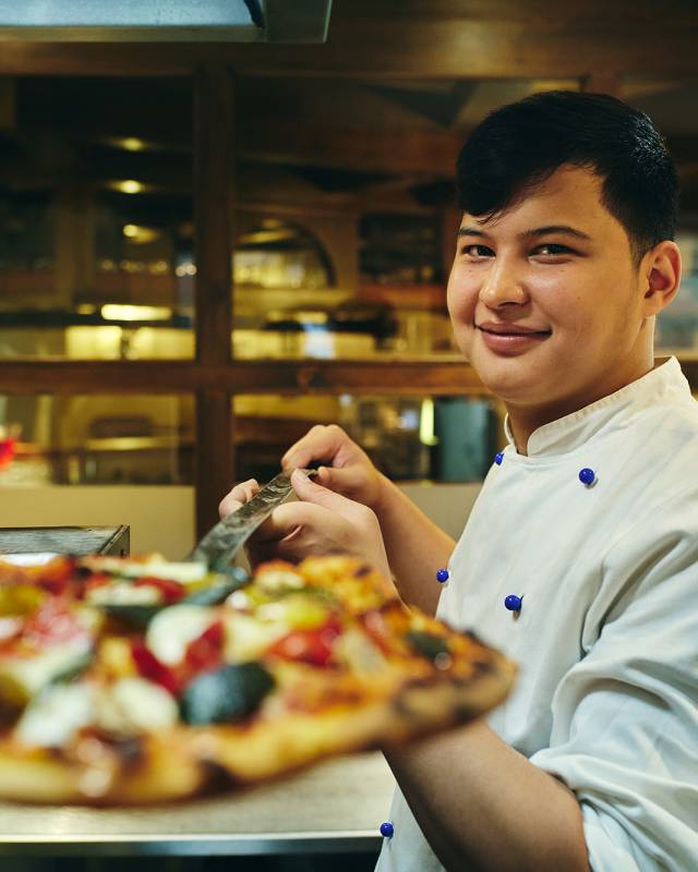 Bäcker holt Pizza aus dem Ofen Sauerland Stern Hotel