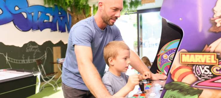 Vater mit Kind am Spielautomat im Indoor Spielplatz des Sauerland Stern Hotel Willingen