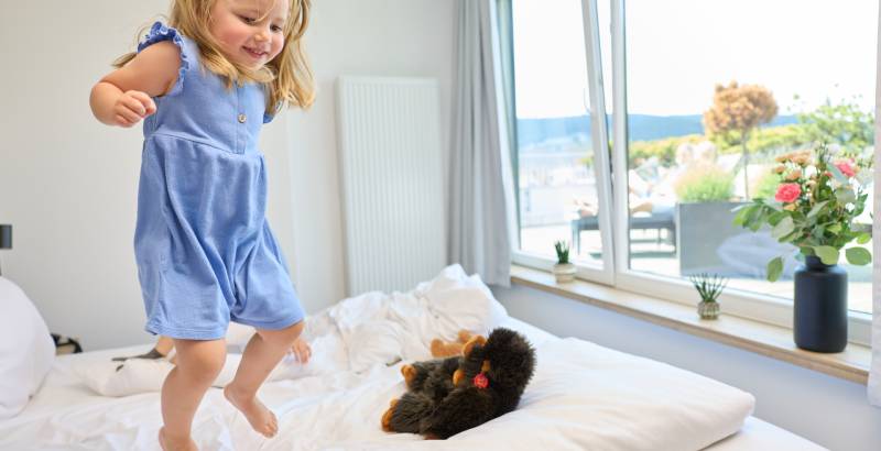 Kind auf dem Bett im Familienzimmer des Sauerland Stern Hotel Willingen